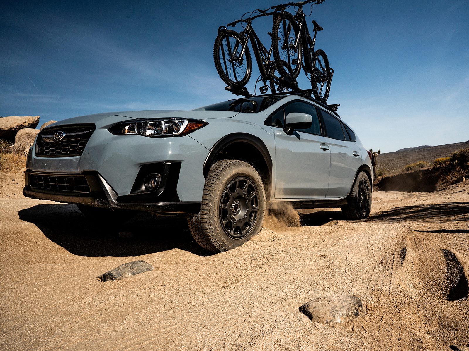 wildpeak all terrain tyres on a new Subaru outback carrying mountain bikes on a sandy mountain road
